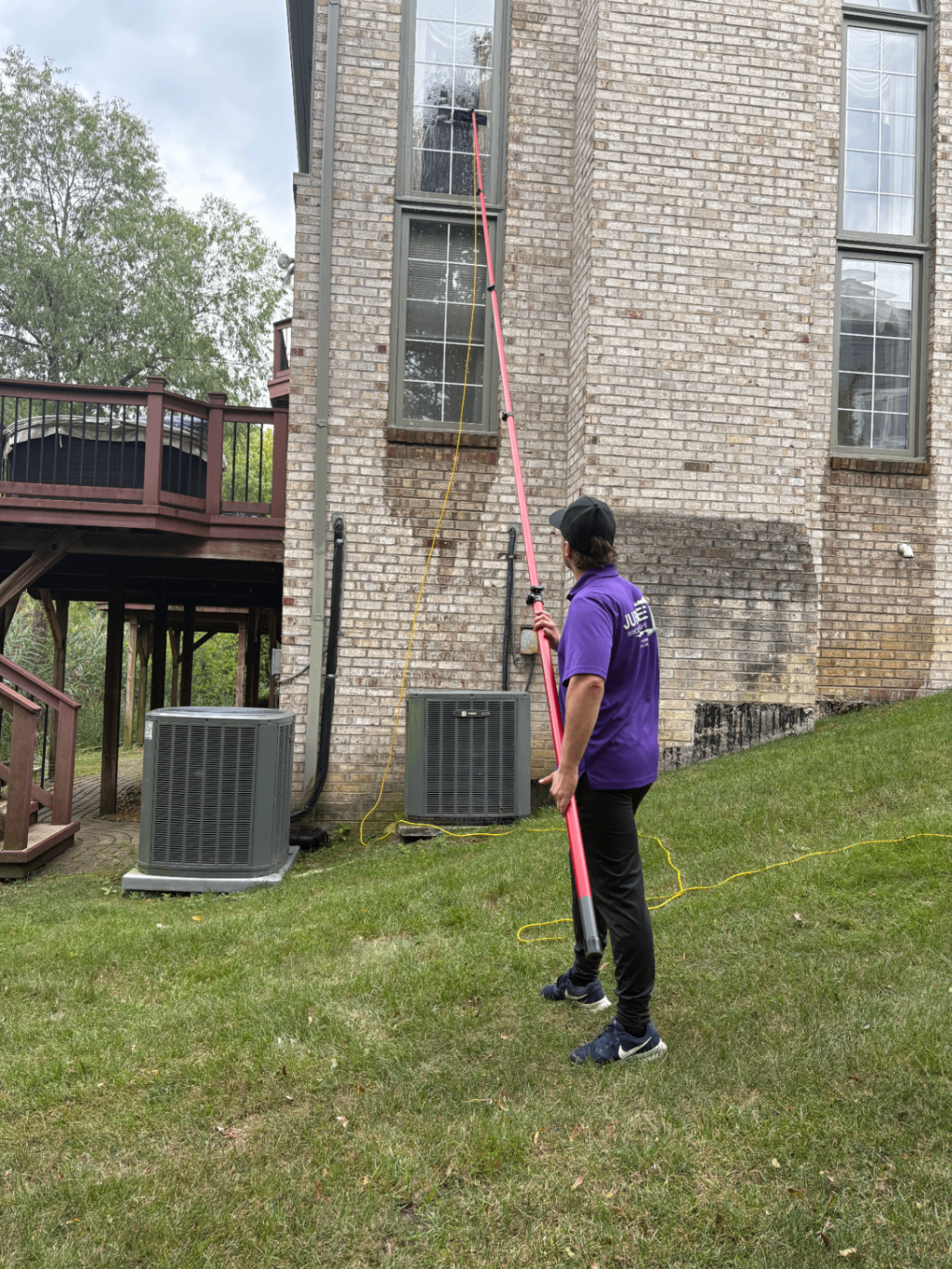 Jubilee Window Washing crew member cleaning second-story windows with a water-fed pole